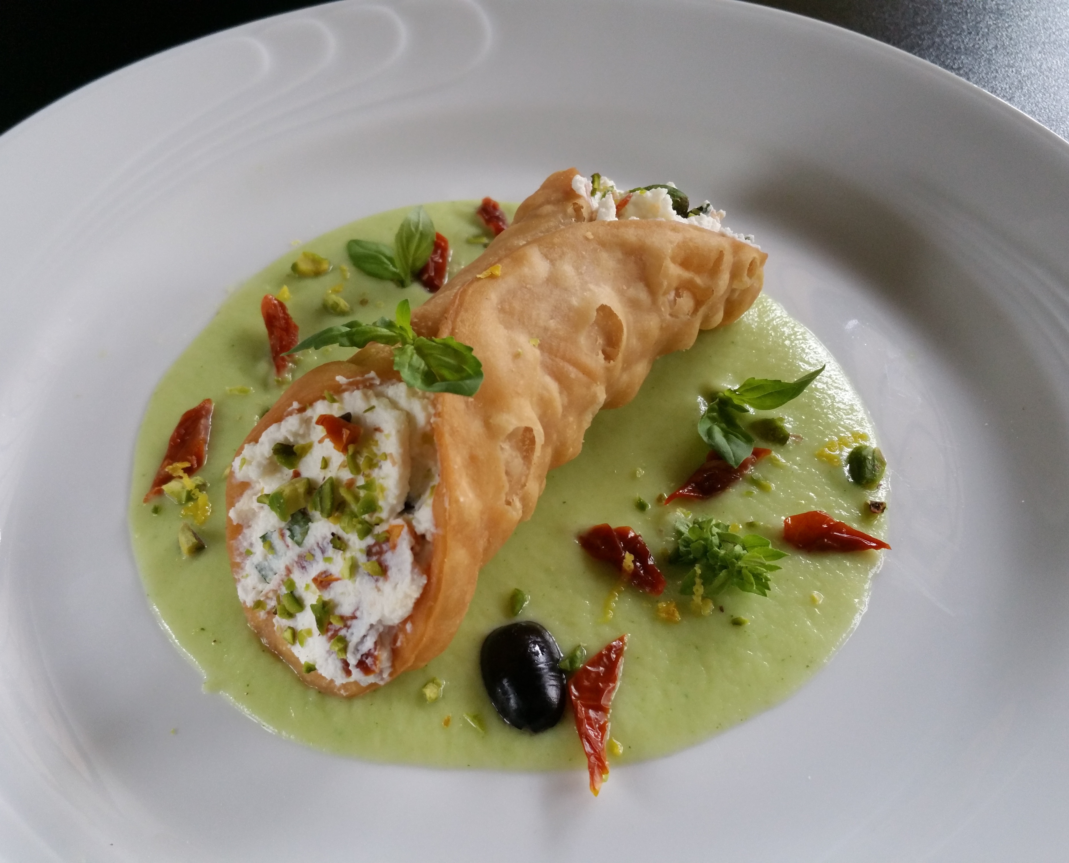 Cannolo salato con ricotta, pomodori secchi, olive leccino e pistacchi su crema di broccoli romani